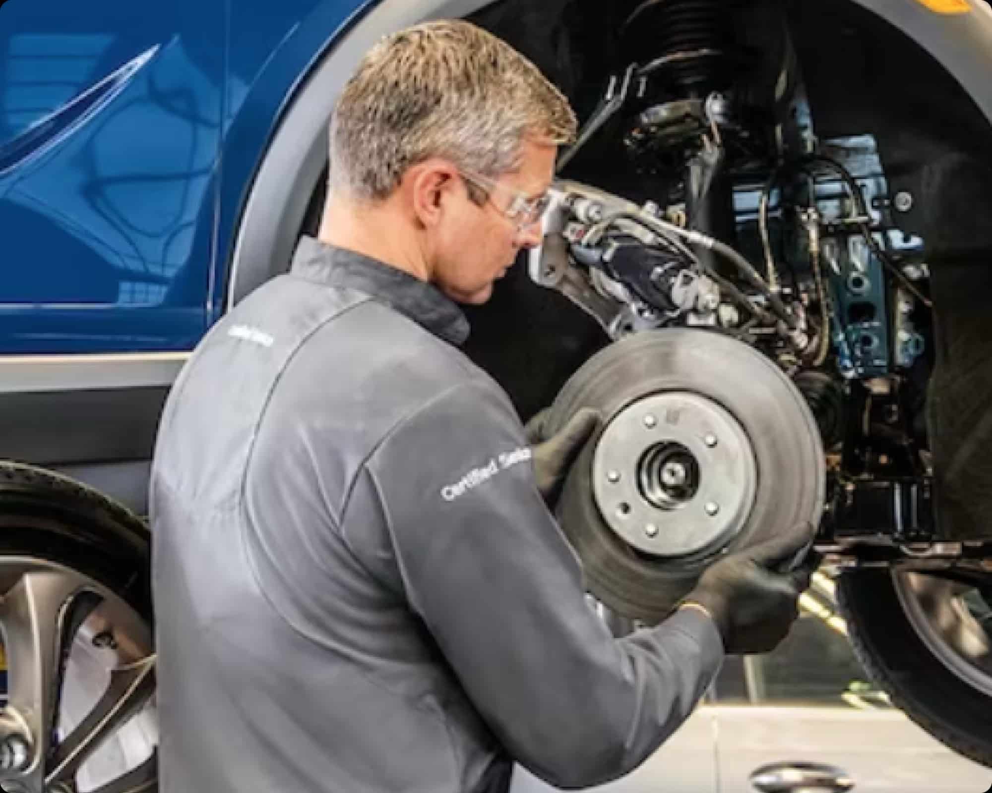 Mechanic replacing a car brake rotor, focusing on vehicle maintenance in a garage setting.