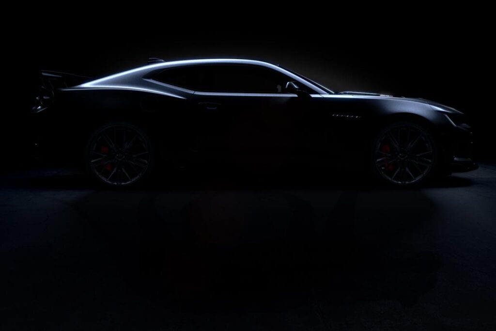 Sleek sports car in shadowy lighting, highlighting its aerodynamic profile and design.