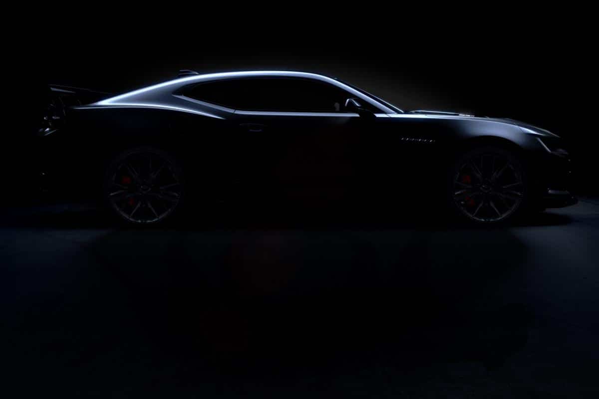 Sleek sports car in shadowy lighting, highlighting its aerodynamic profile and design.
