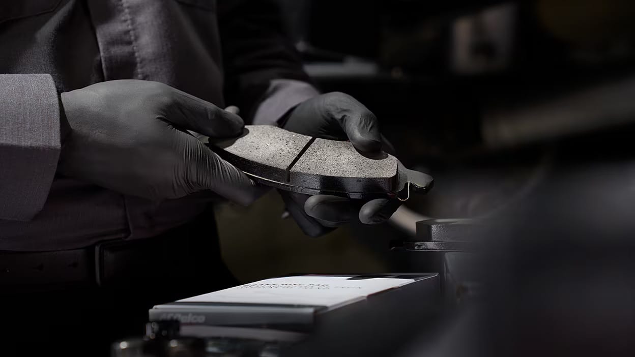 Mechanic in gloves inspecting brake pad, focusing on quality and safety in automotive repair.