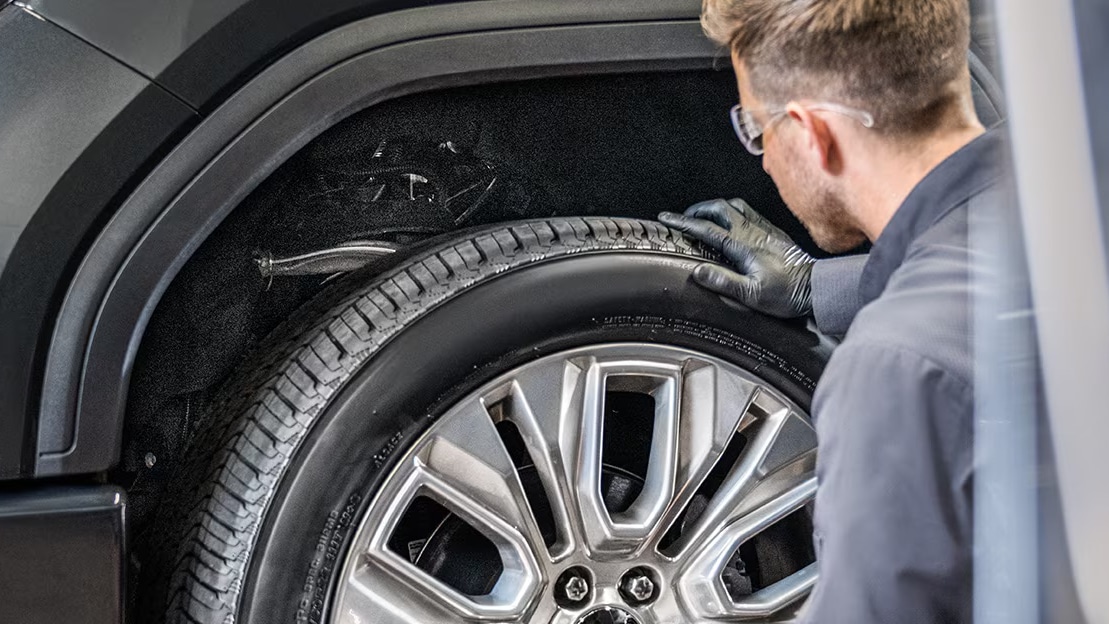 Mechanic inspecting car wheel and tire for maintenance in a garage.