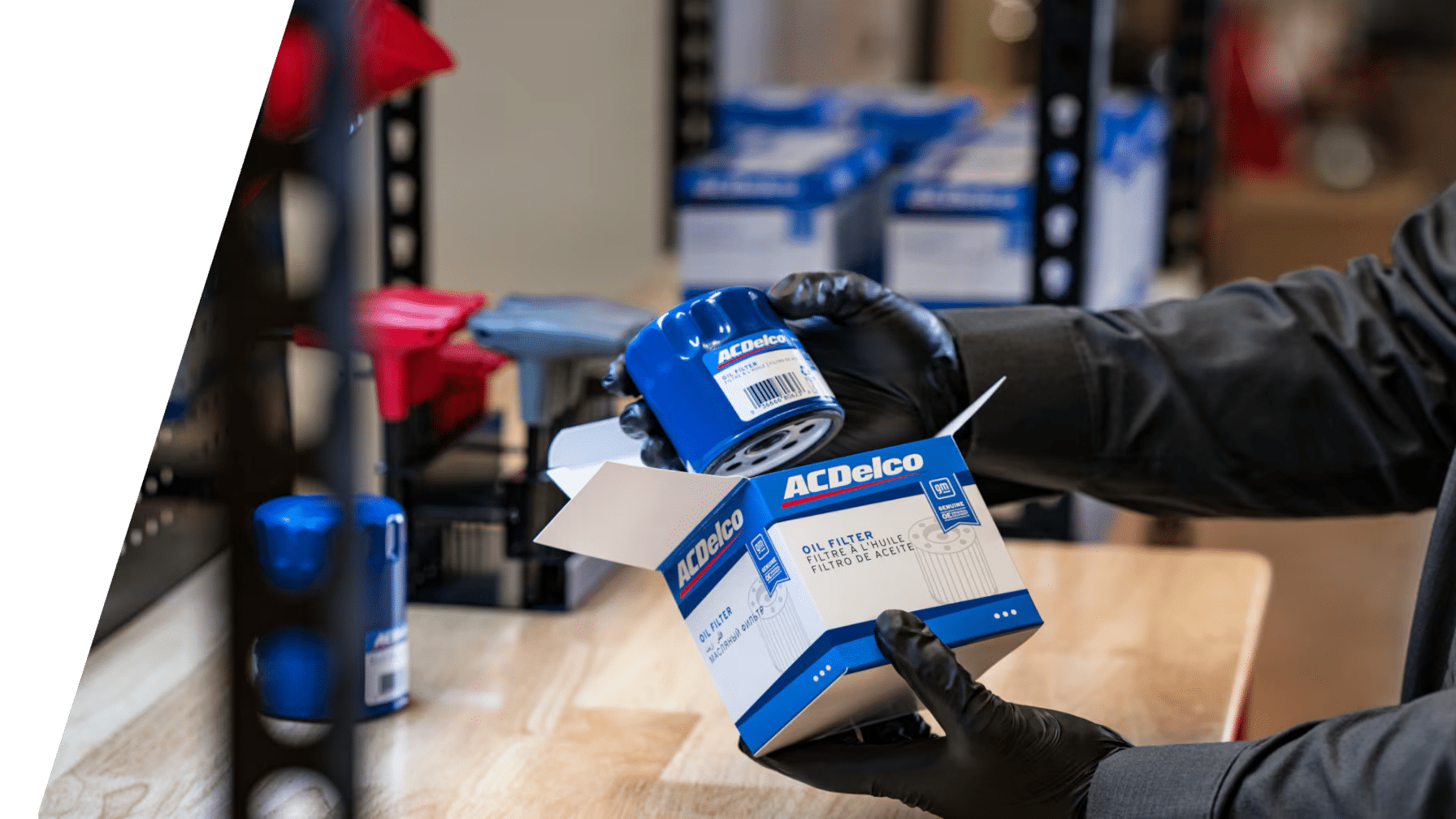 A person in gloves handles an ACDelco oil filter and its packaging on a workbench.