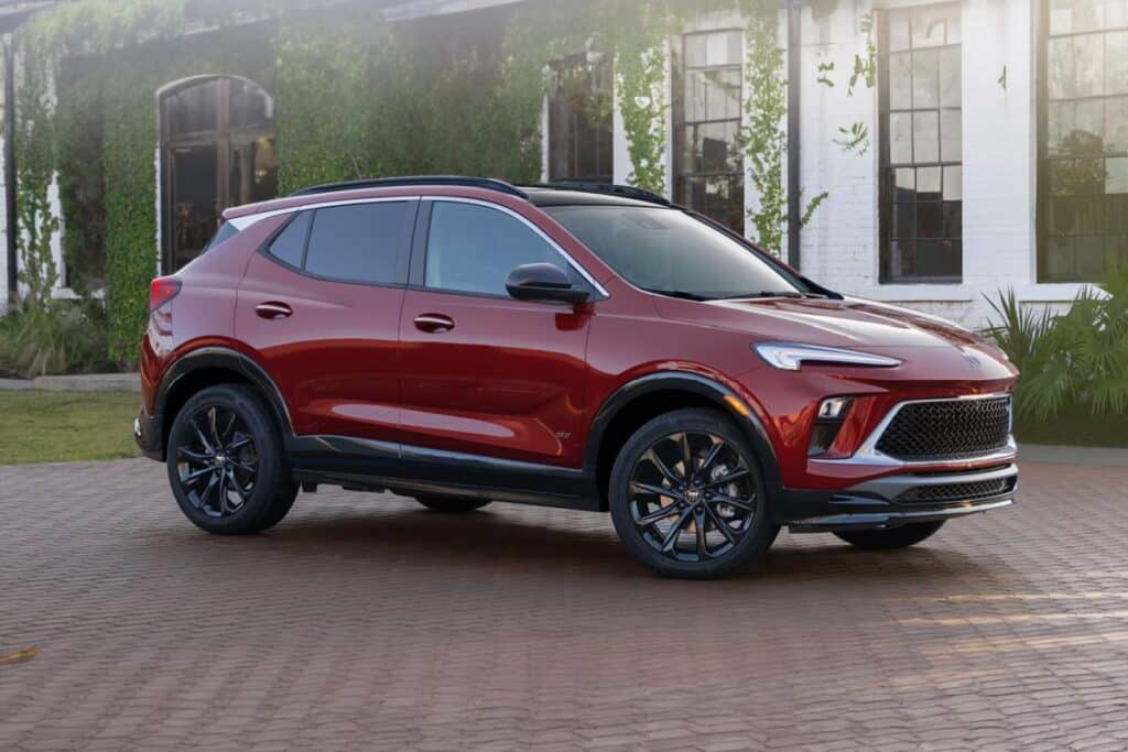 Red SUV parked on a cobblestone driveway in front of a vine-covered building.