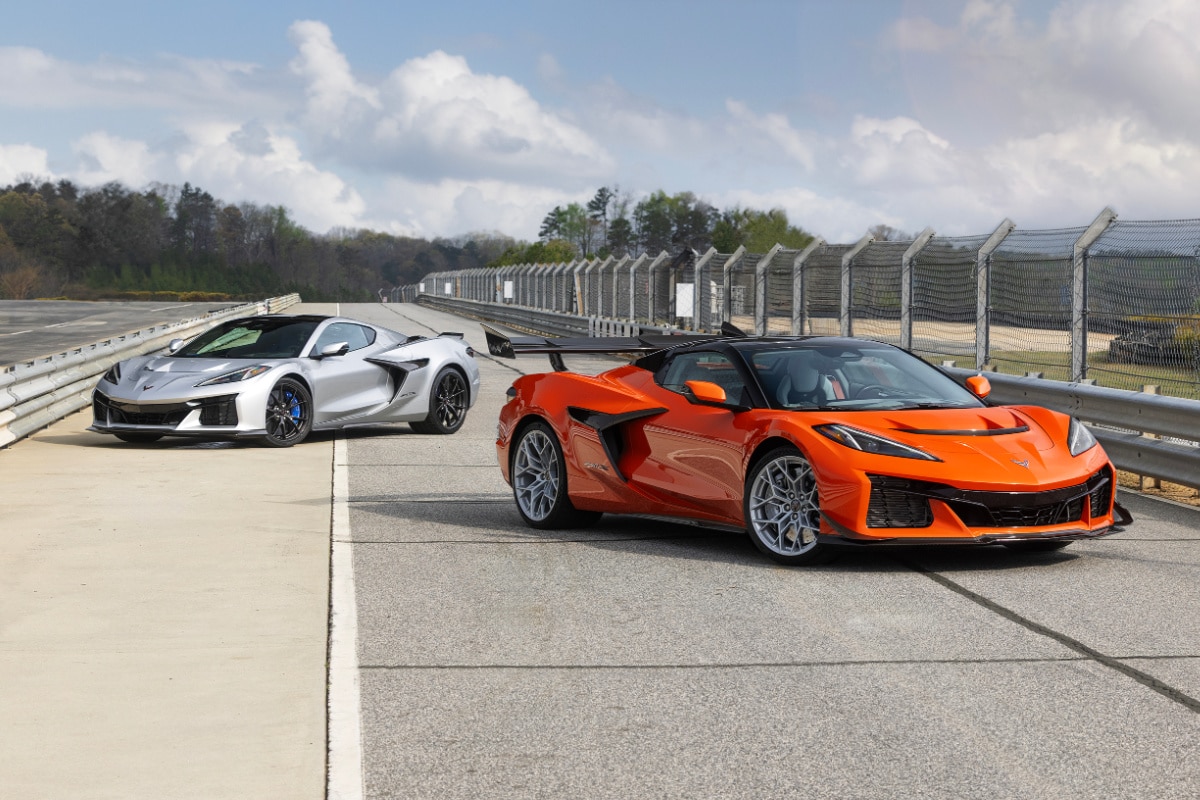Orange and silver sports cars on a racetrack with a cloudy sky in the background.